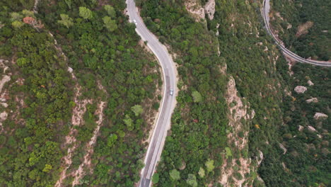 Captivating-drone-top-down-shot-expertly-following-a-car-along-a-winding-mountain-road