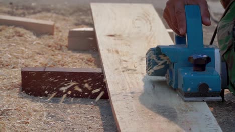 Close-up-shot-hand-of-carpenter-using-planer-machine-to-smooth-the-surface