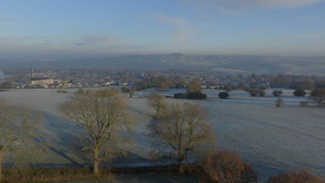 Aufsteigende-Luftdrohnenaufnahme-über-Frostigen-Feldern-Mit-Dem-Dorf-Calverley-Im-Hintergrund,-Leeds,-West-Yorkshire,-Vereinigtes-Königreich