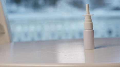 Nasal-spray-bottle-pushed-and-falling-onto-white-surface-table,-slow-motion