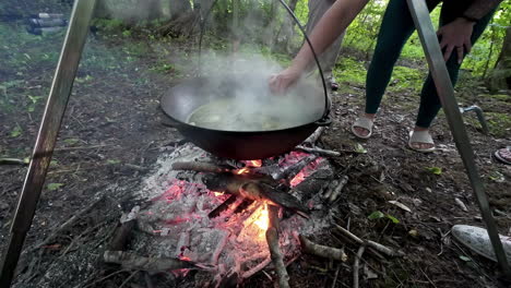 Steaming,-boiling-soup-over-a-campfire---taste-with-a-spoon