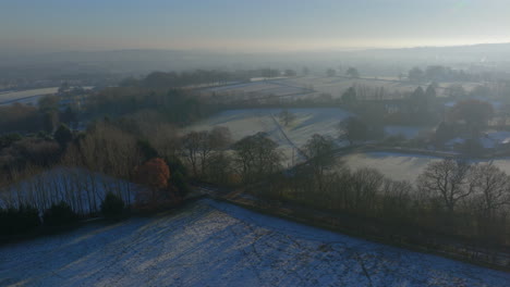 Establishing-Aerial-Drone-Shot-Over-Fields-and-Trees-in-Winter-on-Frosty-Misty-Morning-in-UK