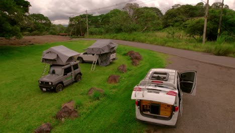 Cinematic-drone-clip-of-camper-4x4-with-tends-camping-outside-in-a-green-pasture-in-nature