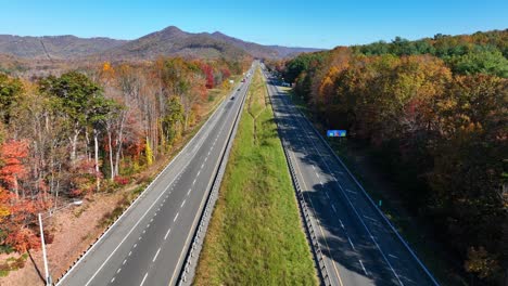 Interstate-highway-in-Appalachia,-lined-by-autumn-trees,-clear-skies