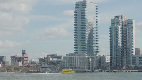 Gelbes-Wassertaxi,-Das-über-Den-East-River-Fährt,-Mit-Wolkenkratzern-Im-Hintergrund-In-New-York