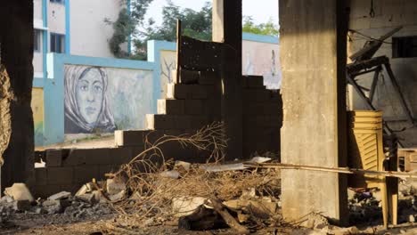 Die-Kamera-Zeigt-Muslimische-Frauenkunst-An-Der-Wand,-Zerstörte-Straße-Von-Gaza-Während-Des-Israel-Hamas-Krieges-2023