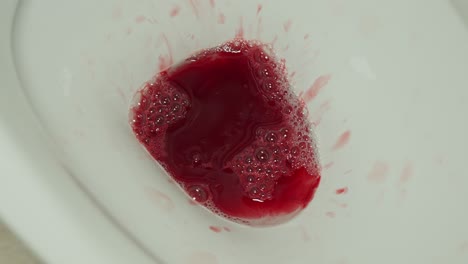 Sangre-De-La-Copa-De-Menstruación-Vaciada-En-El-Baño-Y-Tirada-Hacia-Abajo,-De-Cerca