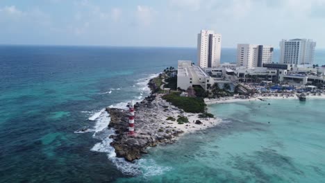 Luftaufnahme-Des-Leuchtturms-Von-Punta-Cancun,-Ein-Herausragendes-Wahrzeichen-In-Cancun,-Mexiko,-Mit-Panoramablick-Auf-Die-Von-Türkisfarbenem-Wasser-Umgebene-Halbinsel