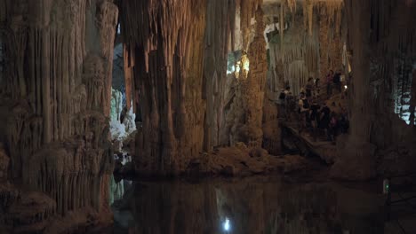 Tourists-visiting-the-Neptune's-Grotto-touring-a-cavern-full-of-stalactites