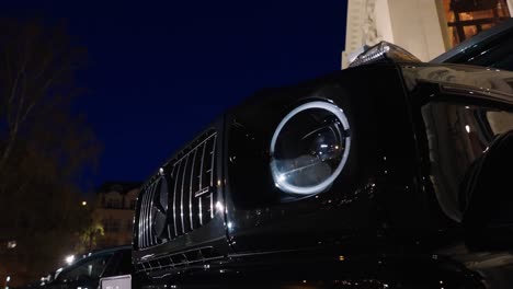 Black-AMG-G-63-Mercedes-car-headlight-turn-on-at-late-evening-motor-show