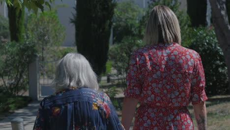 Slow-motion-shot-of-a-grandmother-and-daughter-walking-together-in-a-garden