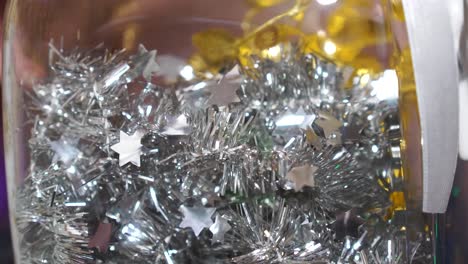 Glänzende-Silberne-Und-Goldene-Weihnachtsdekorationsschnur-Im-Glas,-Frauenhand