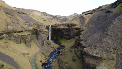 Cinematic-volcanic-river-valley-with-waterfall-Kvernufoss,-Iceland,-aerial-dolly