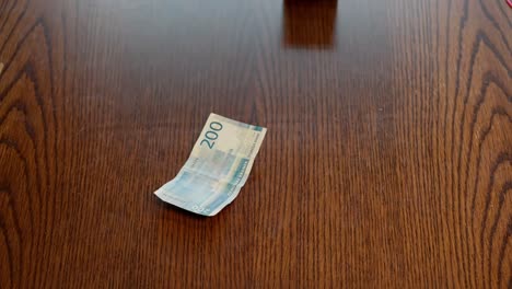 Norwegian-banknotes-falling-down-on-wooden-table-in-slow-motion