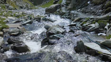 Peaceful-river-stream,-tilt-up-reveal-breathtaking-mountains-in-Valmalenco