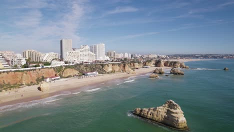 Picturesque-beach-with-rocks-in-the-ocean,-Portuguese-skyline,-aerial-dolly-in