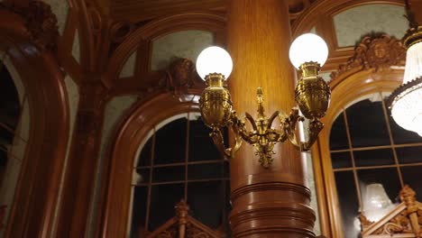 Golden-style-interior-light-bulbs-on-wooden-column-and-chandelier-in-ballroom
