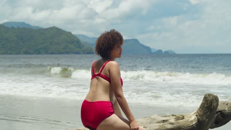 On-a-sunny-day,-a-young-girl-with-curly-hair-relaxes-in-a-red-bikini-on-a-tropical-island
