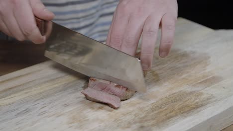 Chef-slicing-beef-cut-on-wooden-board-with-a-chefes-axe