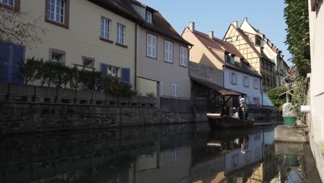 Tourist-motorboat-navigating-tourists-in-the-La-Lauch-river,-flowing-through-the-medieval-town-of-Colmar