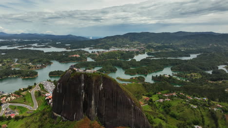Drone-shot-over-the-El-Peñón-rock,-toward-the-reservoir,-in-cloudy-Guatape,-Colombia