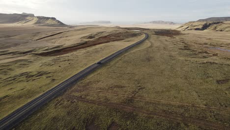 Sunrise-rural-Iceland-panorama-with-black-car-driving-on-road,-aerial-orbit