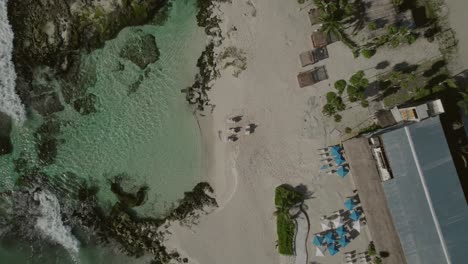 Cinematic-overhead-drone-clip-going-upwards-over-a-tropical-beach-and-beach-resort