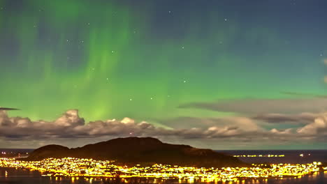 Majestic-Northern-lights-above-glowing-city,-time-lapse-view