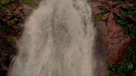 Cinematic-drone-clip-following-down-the-running-water-of-a-beautiful-waterfall