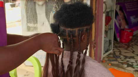 Young-African-woman-undergoing-complex-process-of-hair-extensions-fitting