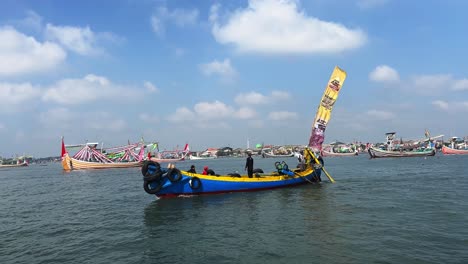 Local-Javanese-Indonesian-fishermen-on-a-boat-with-many-ships-on-background-in-Banyuwangi-during-Patik-Laut-festival-in-Muncar-village