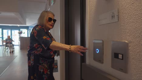 Slow-motion-shot-of-an-elderly-woman-pressing-the-lift-button-in-a-retirement-home