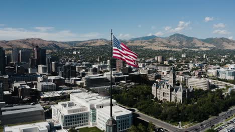 Aerial-view-of-a-flag-overlooking-Salt-Lake-City's-downtown-sector-on-a-sunny-day