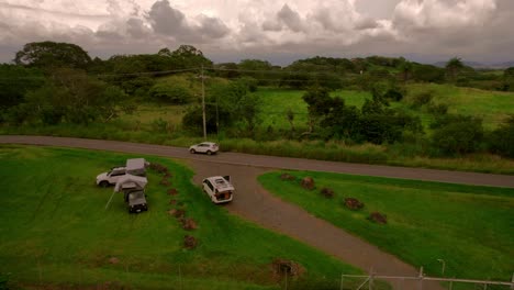 Clip-Cinematográfico-De-Drones-De-Una-Caravana-4x4-Con-Tiendas-Acampando-Afuera-En-Un-Pasto-Verde-En-La-Naturaleza