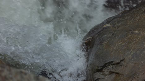 Detail-closeup-of-water-splashing-powerfully-against-rock,-mountain-waterfall