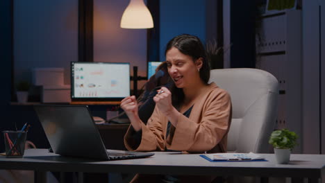 Joyful-successful-businesswoman-enjoying-while-looking-at-laptop-computer