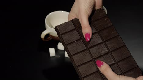 Frau-Zerbricht-Tafel-Schwarze-Schokolade.-Nahaufnahme-Der-Finger-Einer-Frau