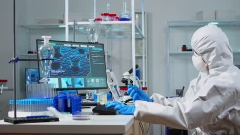 Wissenschaftler-Im-PSA-Anzug-Halten-Reagenzglas-Mit-Blauer-Flüssigkeit-Im-Sterilen-Labor