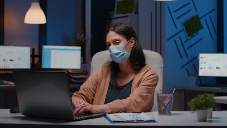Workaholic-businesswoman-with-face-mask-against-covid19-working-in-startup-office
