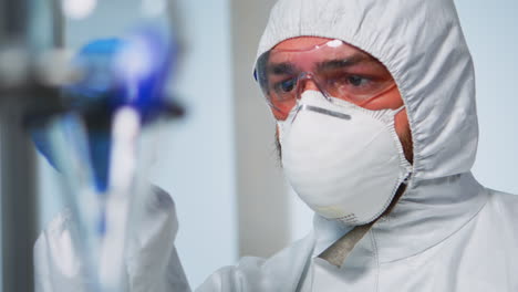 Close-up-of-chemist-holding-blood-sample-wearing-coverall