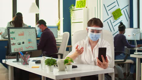 Emploee-with-face-mask-using-having-videocall-on-smartphone