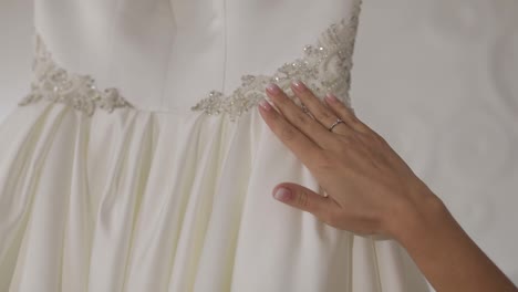 Hand-of-beautiful-bride-touches-wedding-dress.-Pretty-and-well-groomed-woman