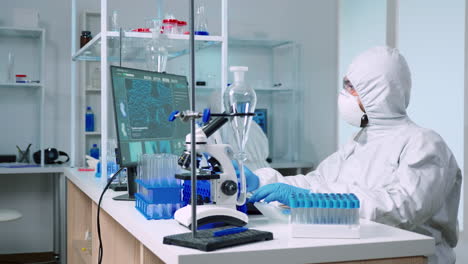 Chemist-in-protection-suit-examining-various-bacteria-holding-petri-dish