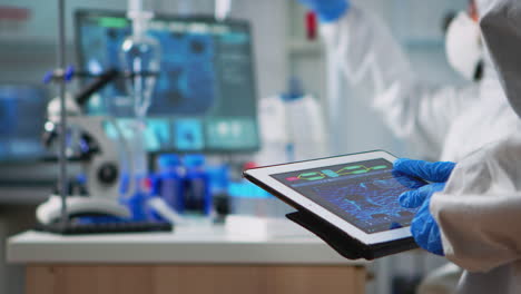 Scientist-in-coverall-analyzing-virus-evolution-looking-on-digital-tablet