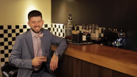 Groom-with-a-black-beard-with-a-glass-of-alcohol-whiskey-in-bar.-Businessman