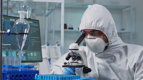 Close-up-of-scientist-looking-through-a-microscope-wearing-ppe-suit