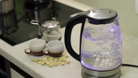 Tea-kettle-with-boiling-water.-Tea-bags-and-sugar-on-the-background