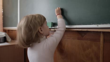 Girl-drawing-at-blackboard-using-a-chalk-in-classroom.-Education-process