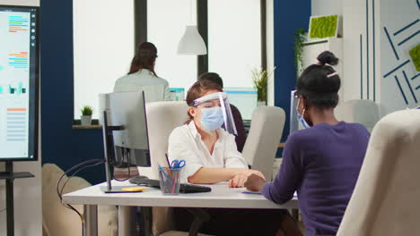 African-employee-and-coworker-with-face-masks-planning-project