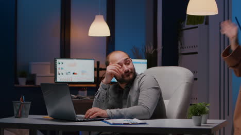 Exhausted-businessman-checking-marketing-statistics-on-laptop-computer